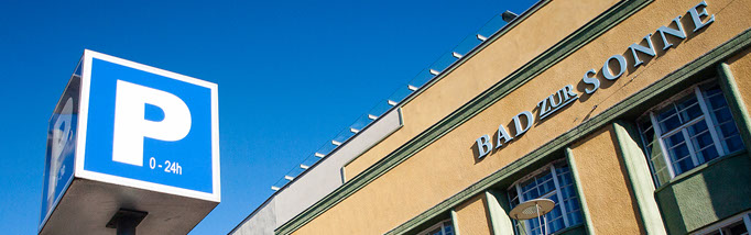 Fassade Bad zur Sonne mit blauem Parkschild, 0 bis 24 Uhr